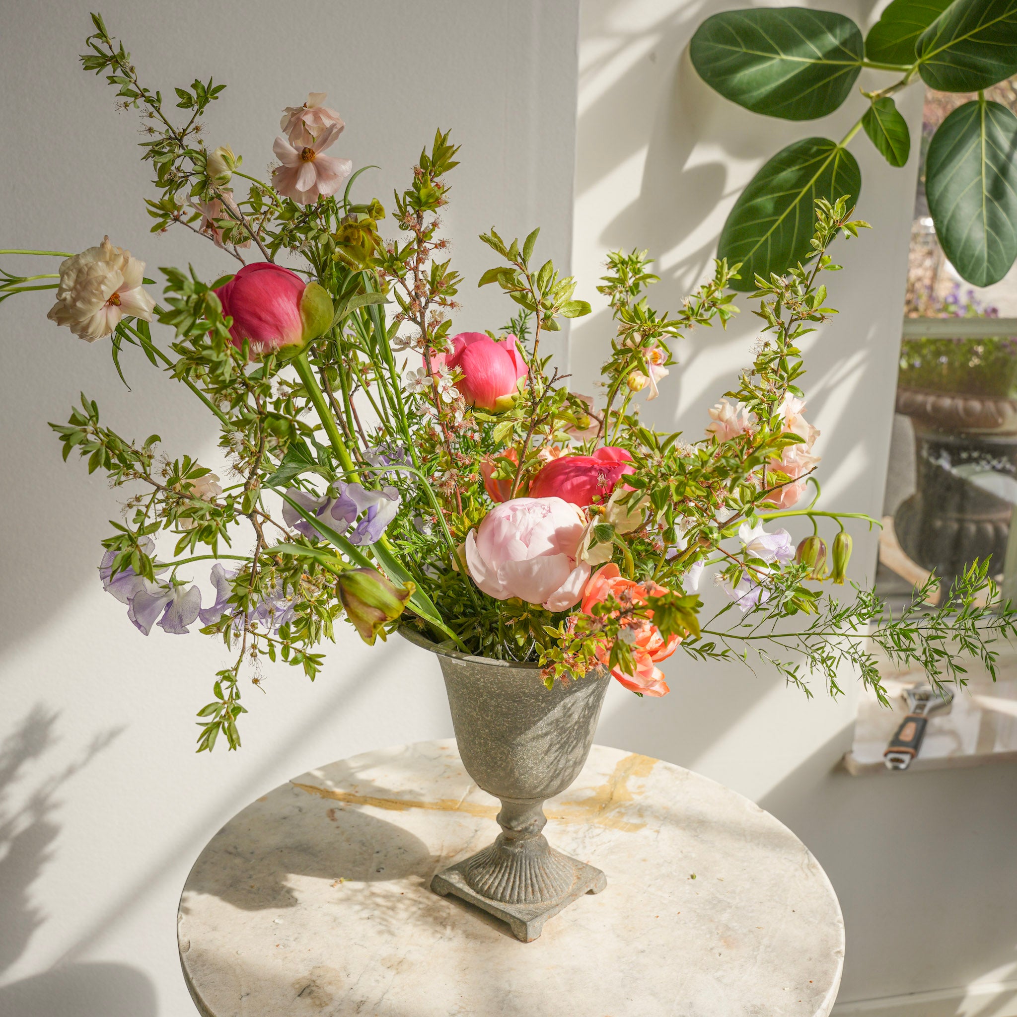 Floral arrangement in a decorative vase on a marble surface with a white wall background