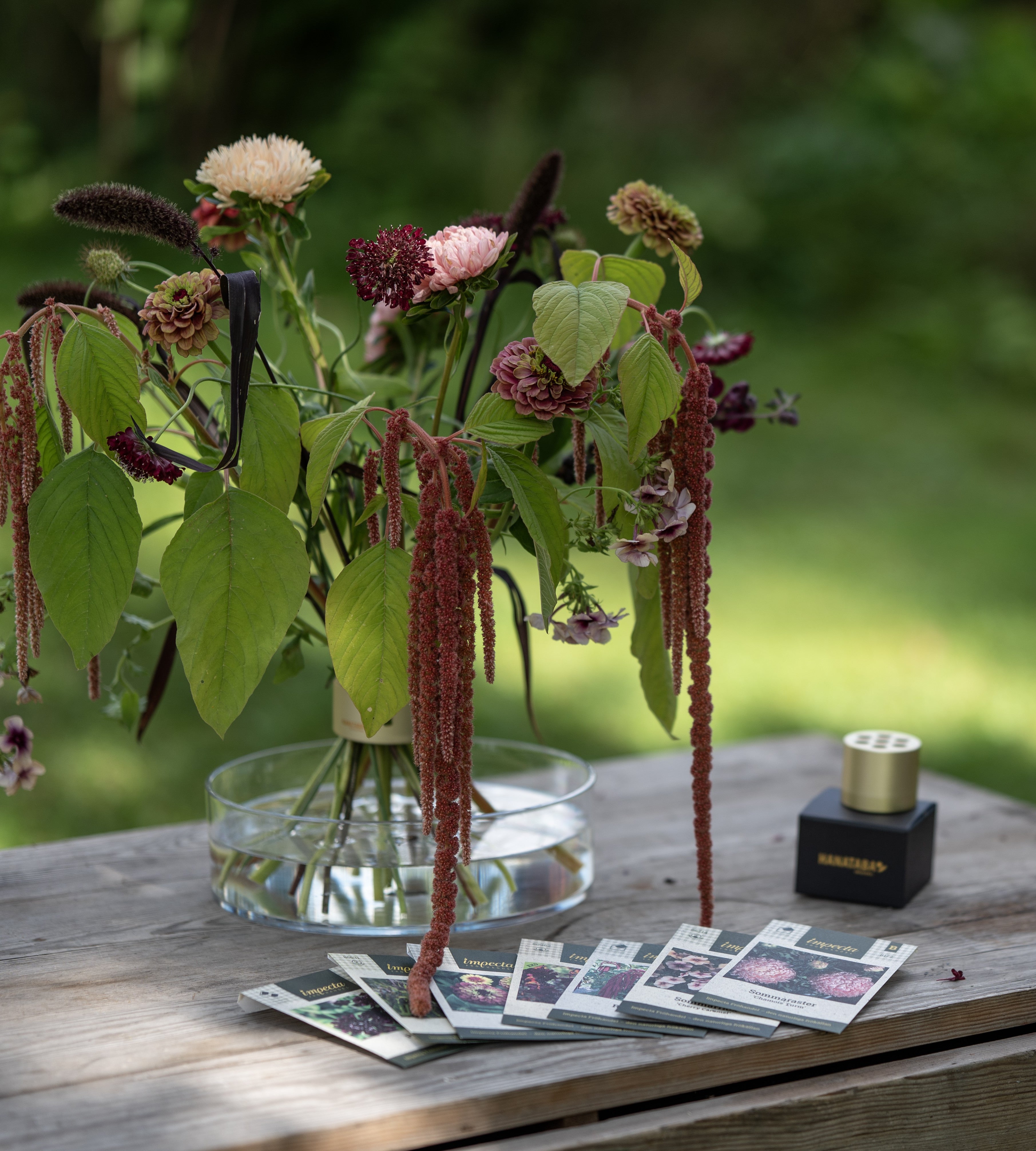 Vase with flowers and decorative elements on a wooden table outdoors
