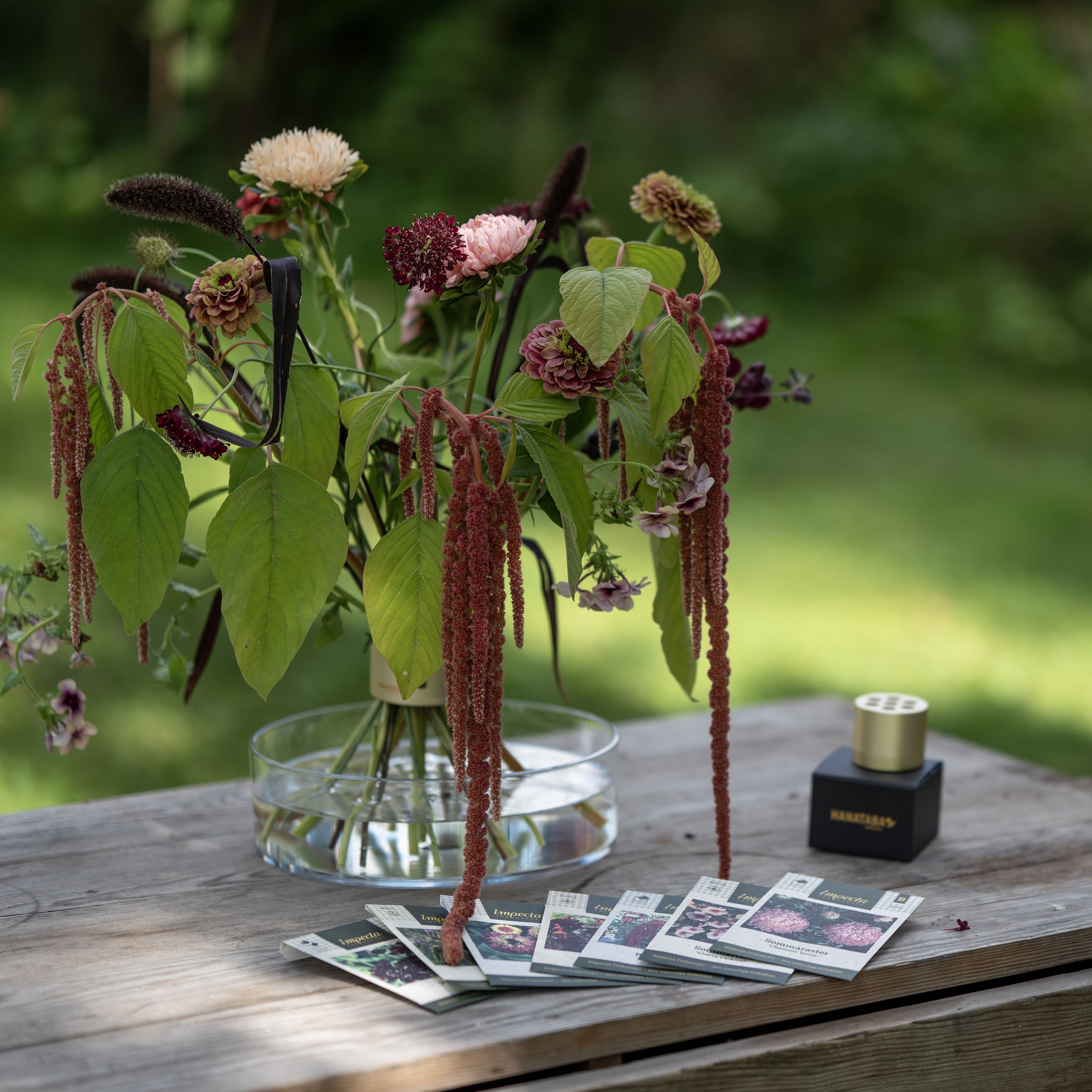 Vase with flowers and decorative elements on a wooden table outdoors