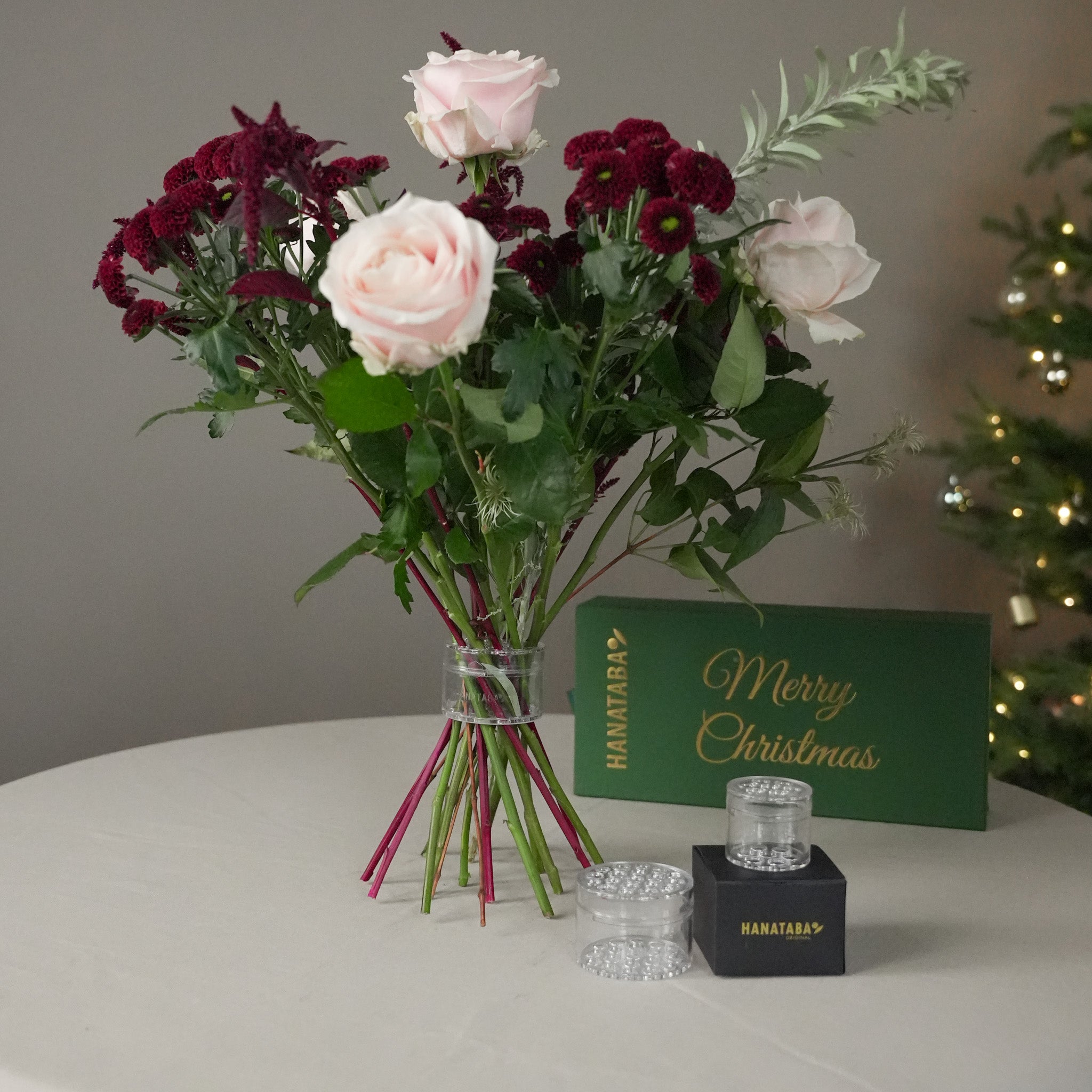 Elegant flower bouquet arranged with Hanataba Crystal Clear, displayed beside the green Merry Christmas gift box. The perfect holiday gift for floral design lovers.