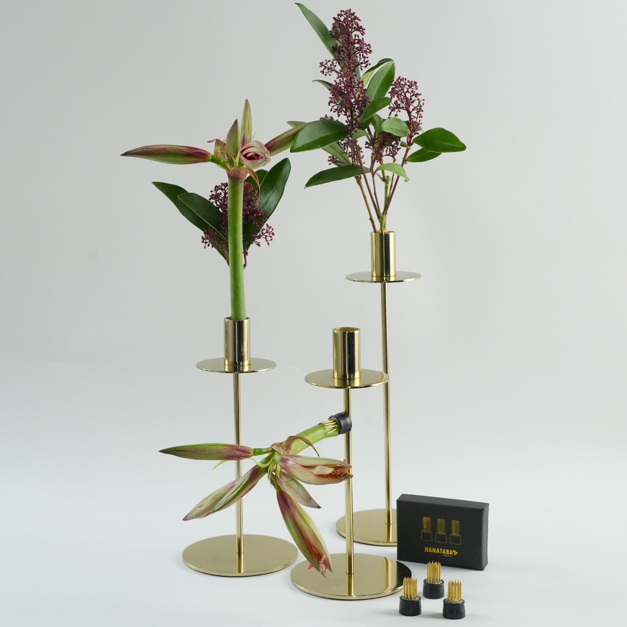 Hanataba Magnetic Mini Kenzan in three gold cylindrical candle holdlers with flowers on a white background