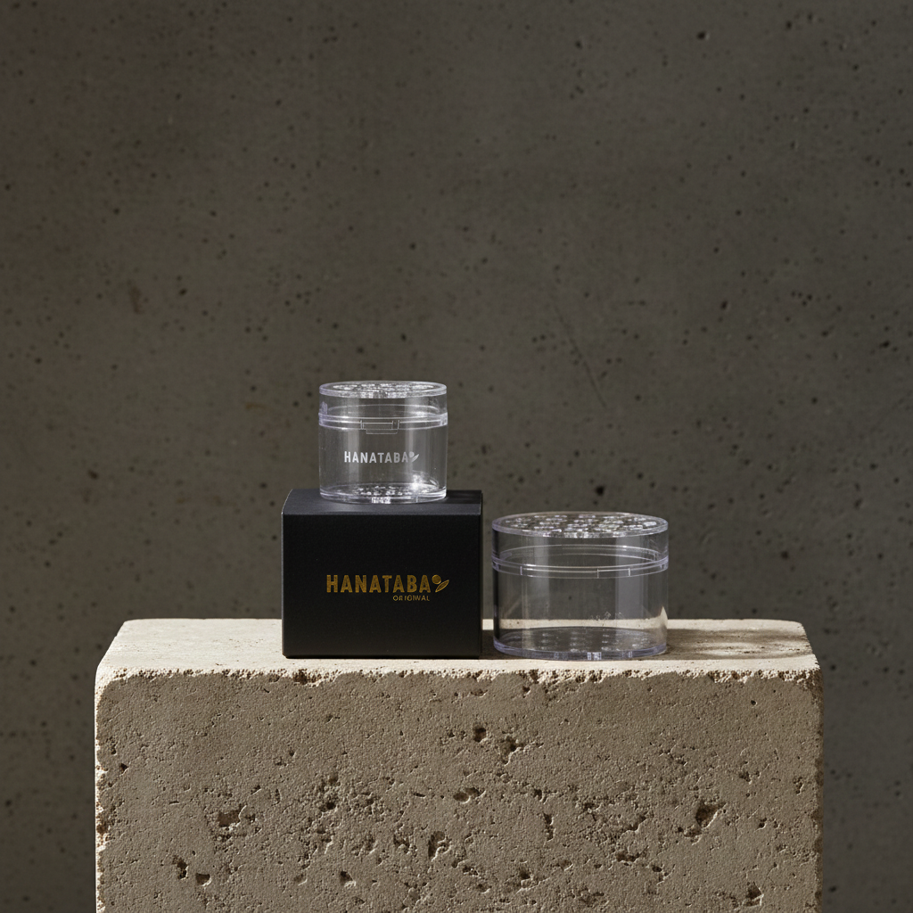 Two clear Hanataba bouquet flower twisters used for creating bouquets without experience. 2 sizes, large and small fitting from 7 to 30 flowers through the holes. Standing on a concrete stand with 'HANATABA' branding against a gray background.