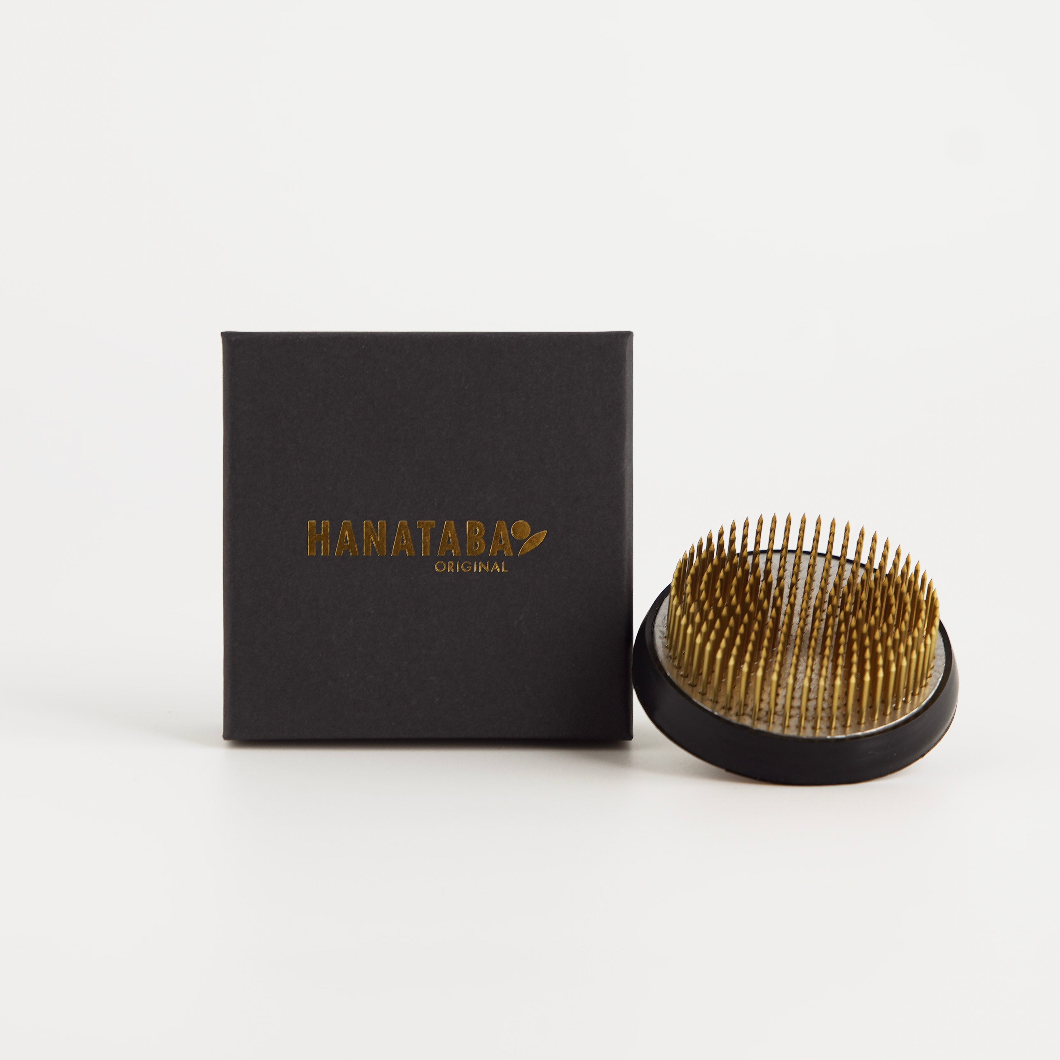 Kenzan 70 mm flower frog pin stem holder next to a black box with 'HANATABA' branding on a white background