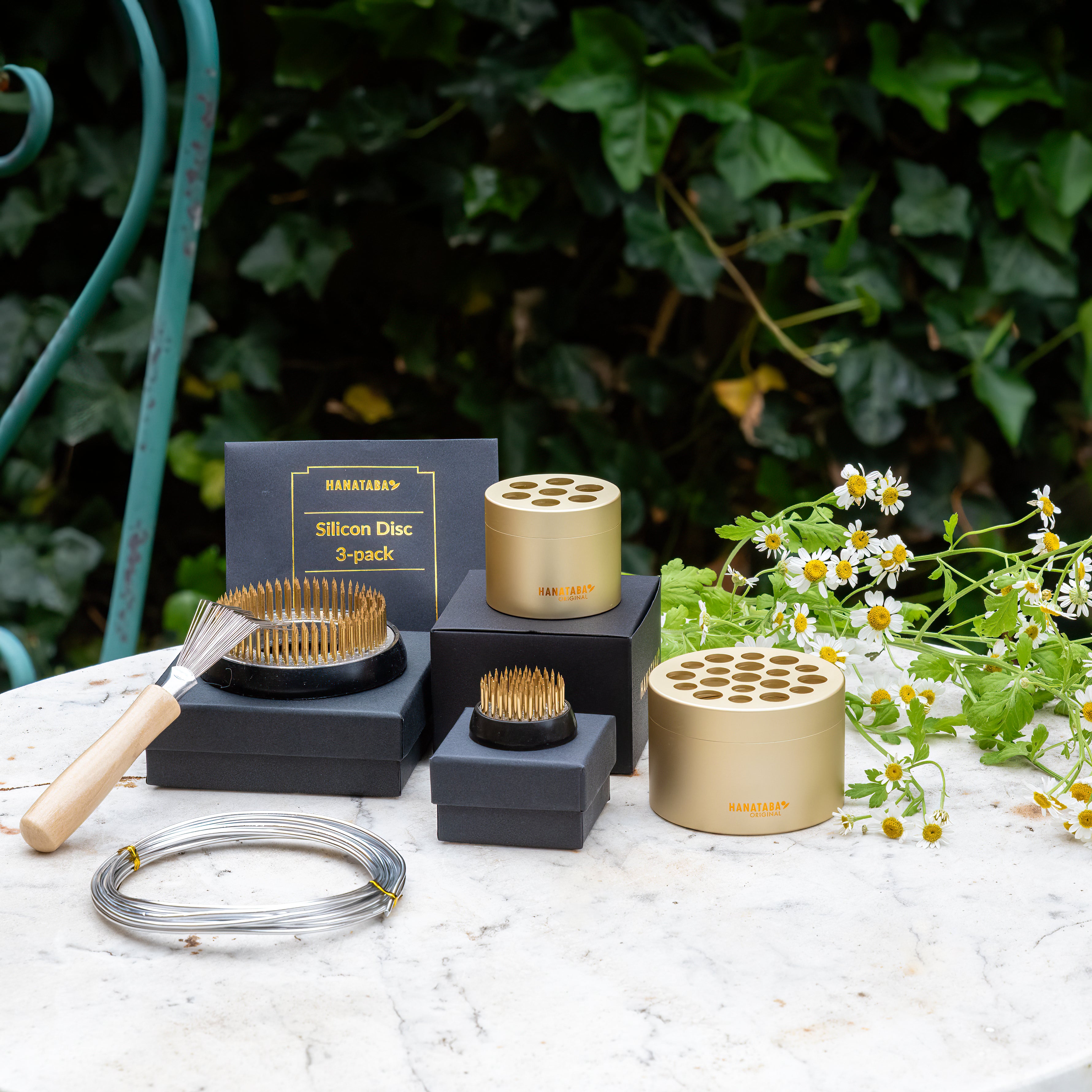 Collection of gardening and flower arrangement tools by Hanataba and accessories on a table with a natural background
