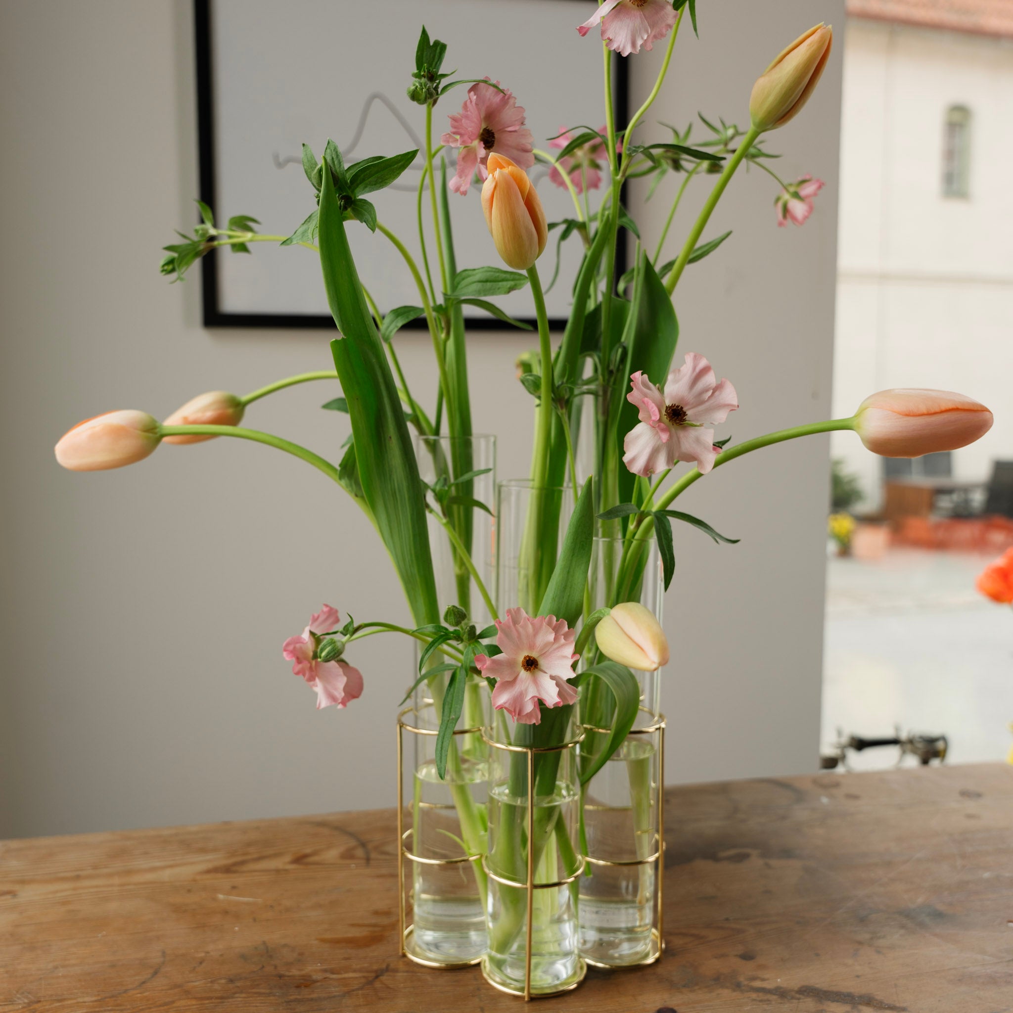 Floral arrangement in a glass 'Milano' vase with gold base on a wooden table