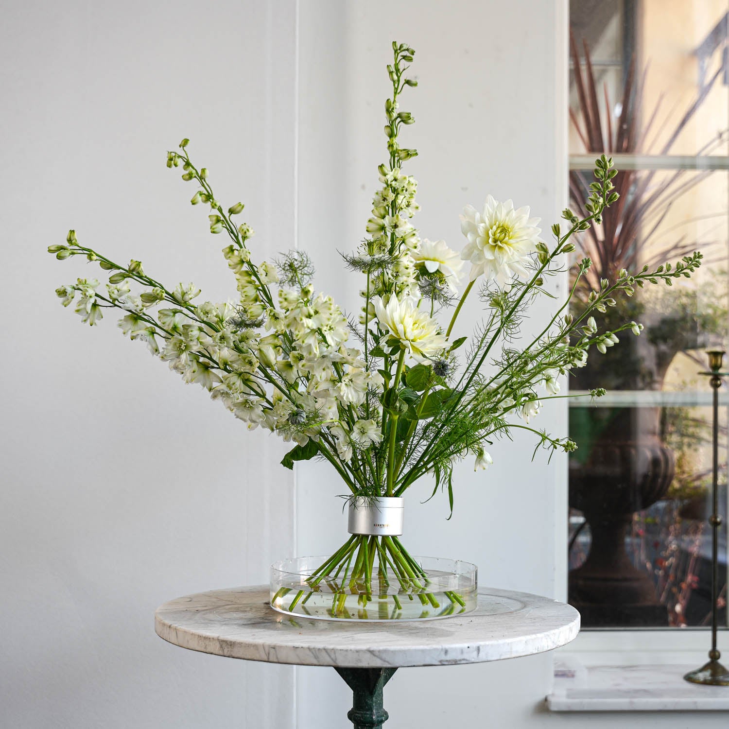 Bouquet of white flowers in a clear vase on a marble table with a neutral background