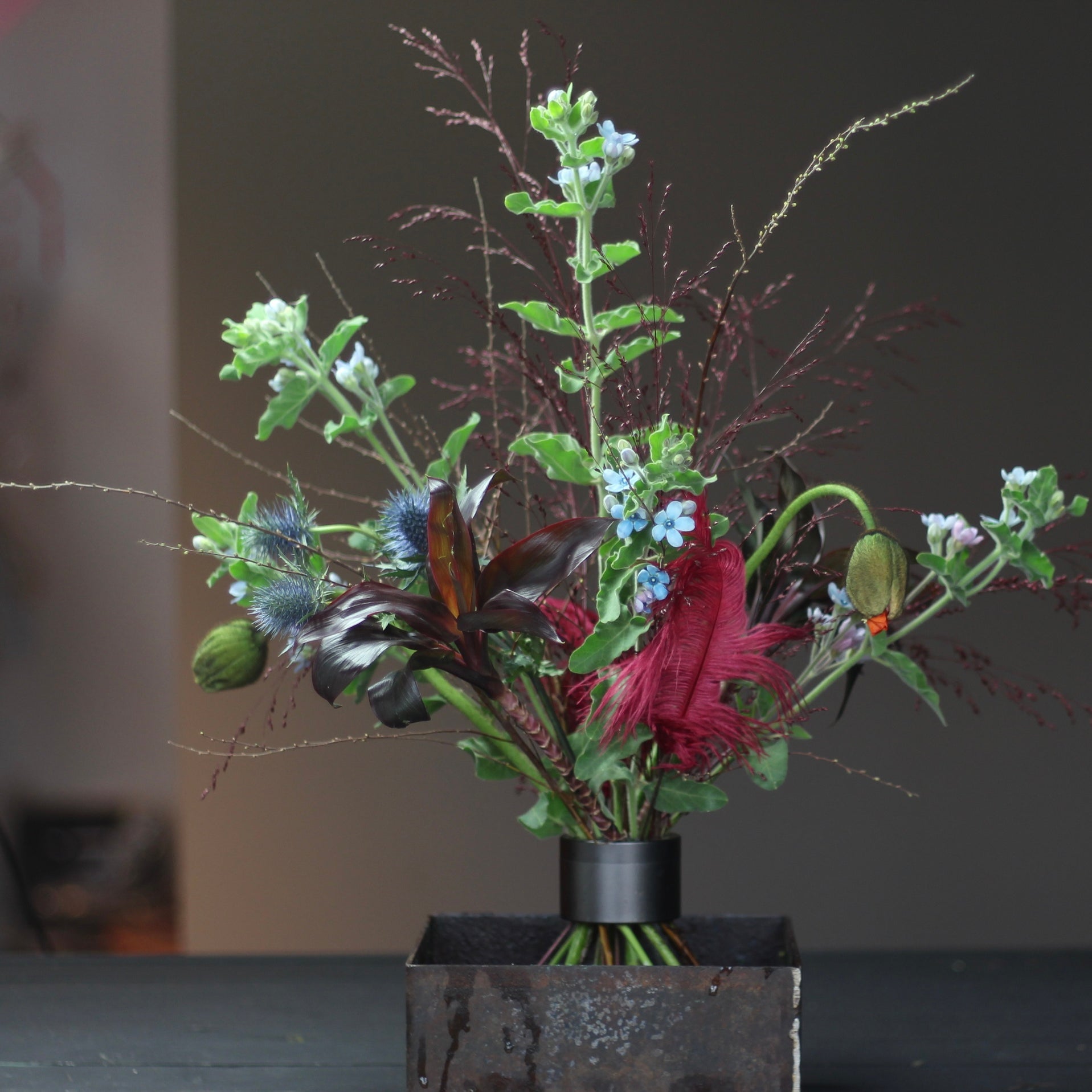 Ikebana arrangement featuring a variety of flowers and foliage secured with a Hanataba pitch black spiral stem holder.