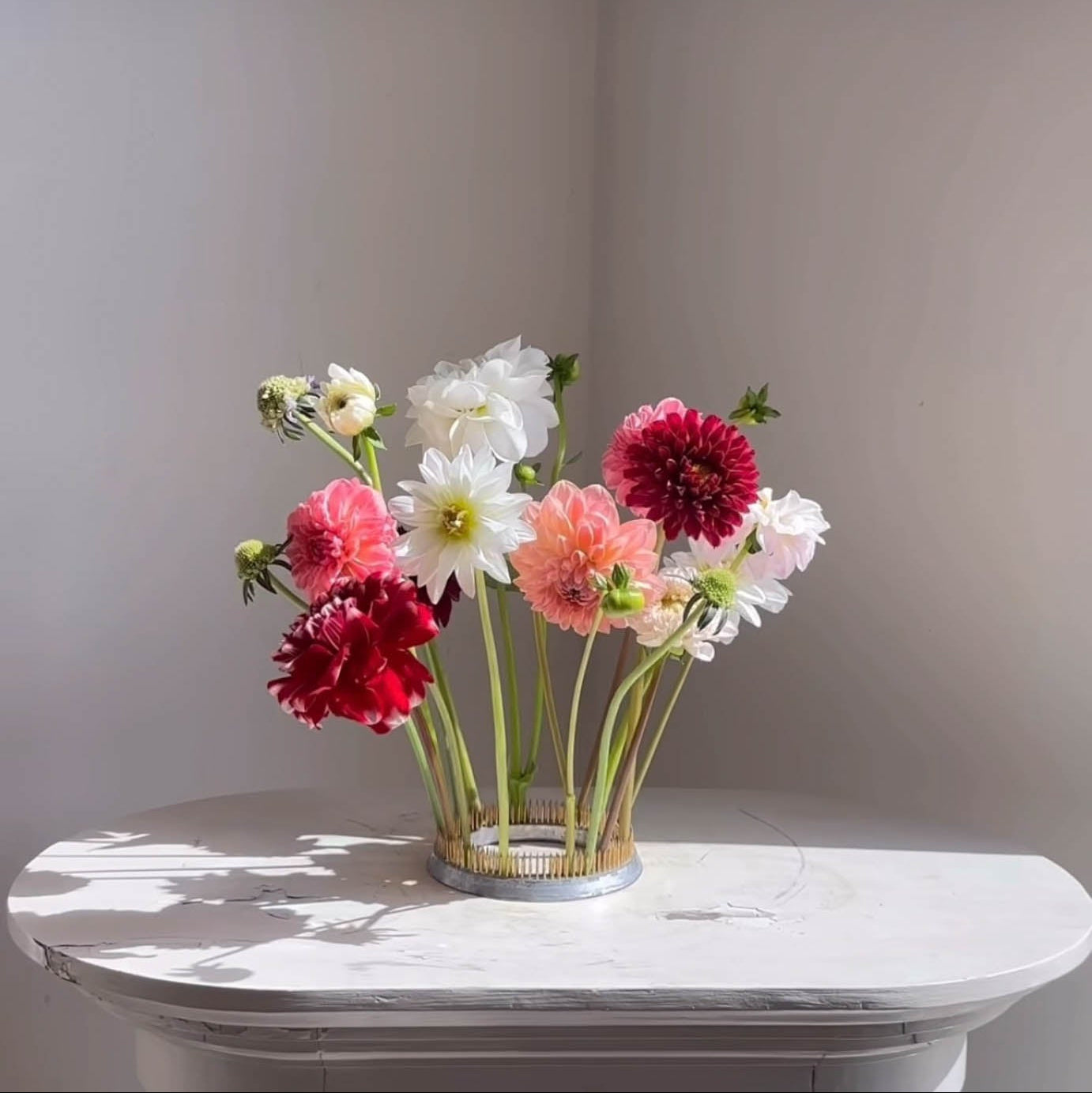 Bouquet of colorful flowers set on a kenzan ring 120 mm on a marble surface with a neutral background