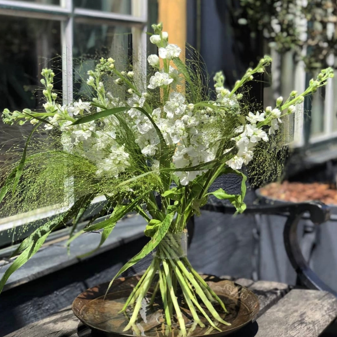 An Ikebana arrangement featuring an assortment of delicate white flowers, complemented by a Hanataba Crystal Clear Spiral Stem Holder for a modern touch.