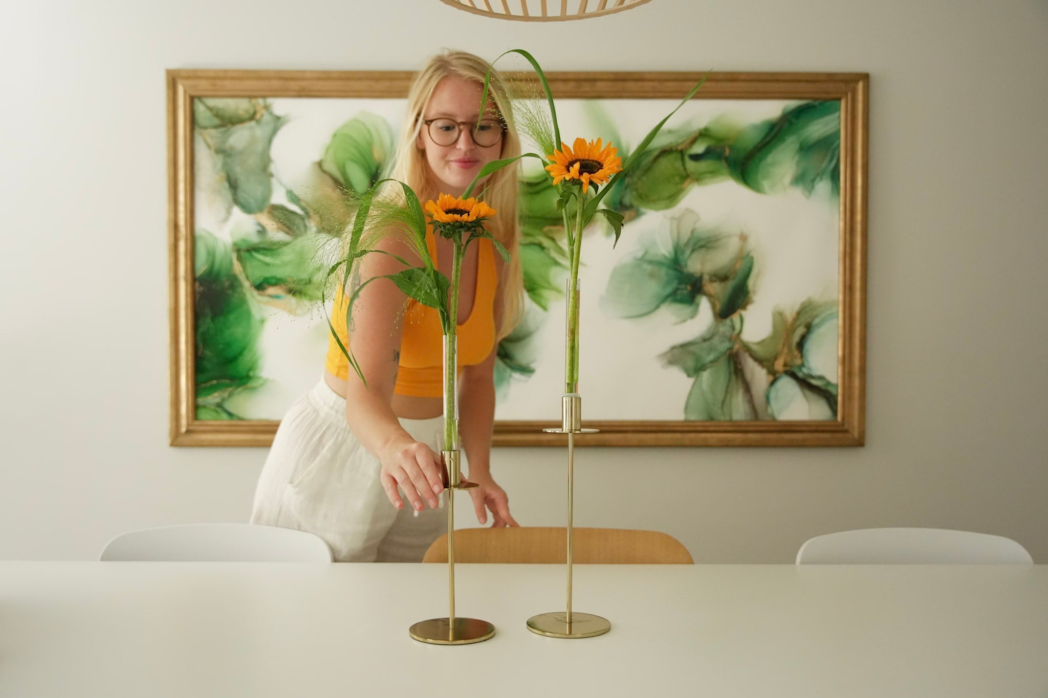 Woman arranging sunflowers in minimalist candle vases on table - Hanataba flower styling at home