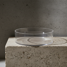 Clear acrylic bowl on a concrete surface with a dark background