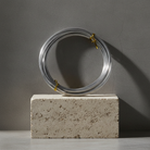 Silver coiled metal bonsai wire on a concrete block against a gray background
