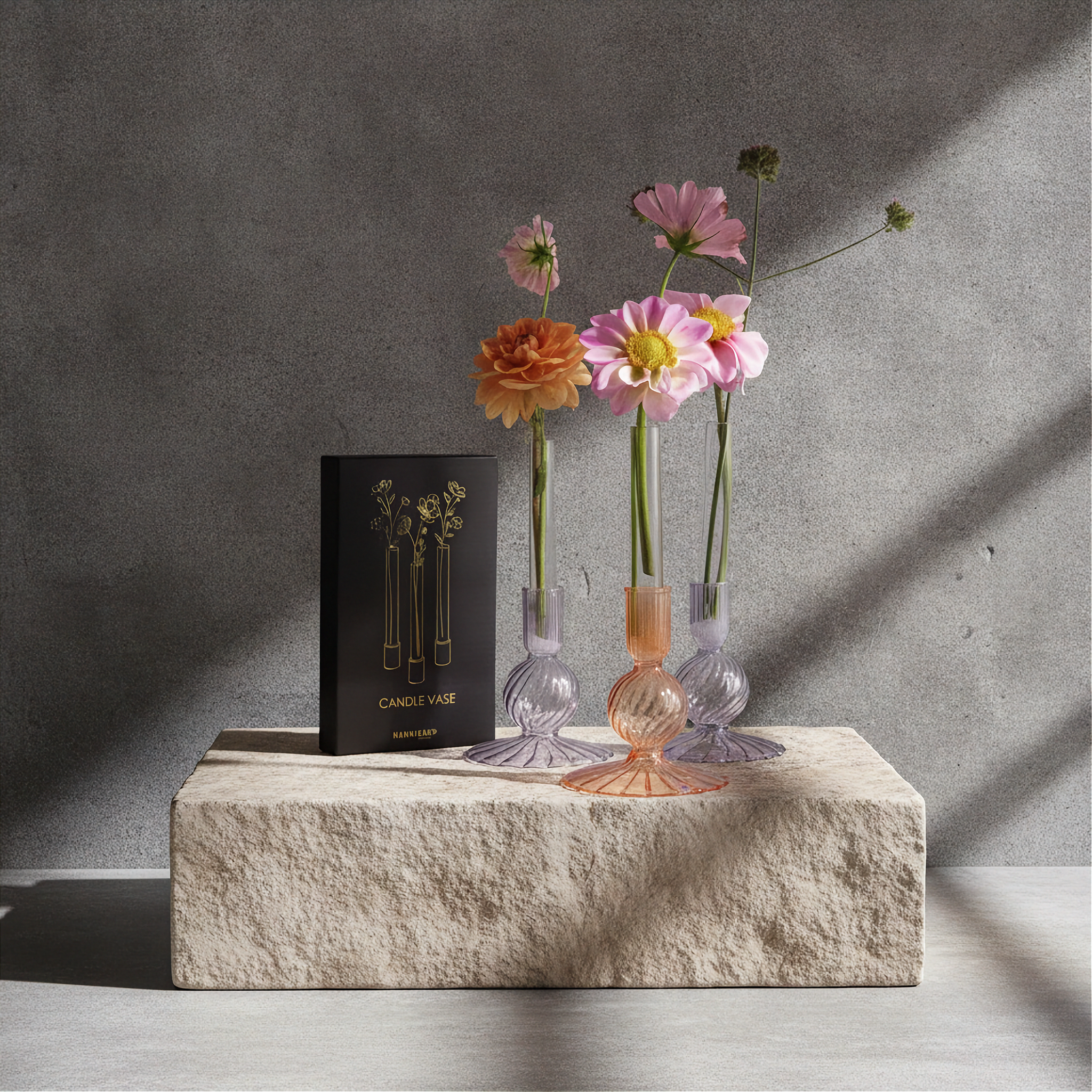Three small glass vases with flowers on a stone surface against a gray wall. Candle vase 3-pack by Hanataba
