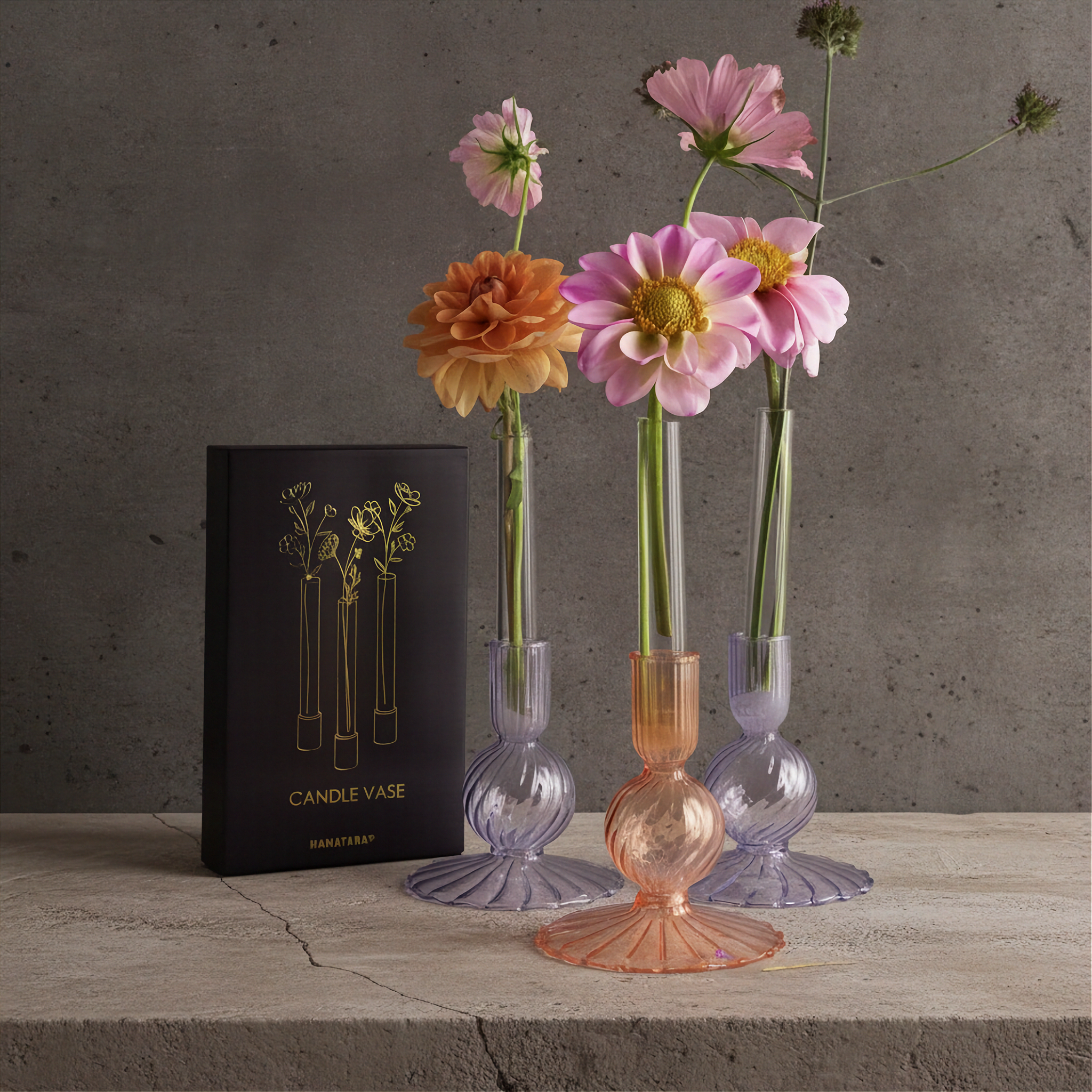Three Hanataba Candle vases set in three candles holders displayed with pink and orange flowers