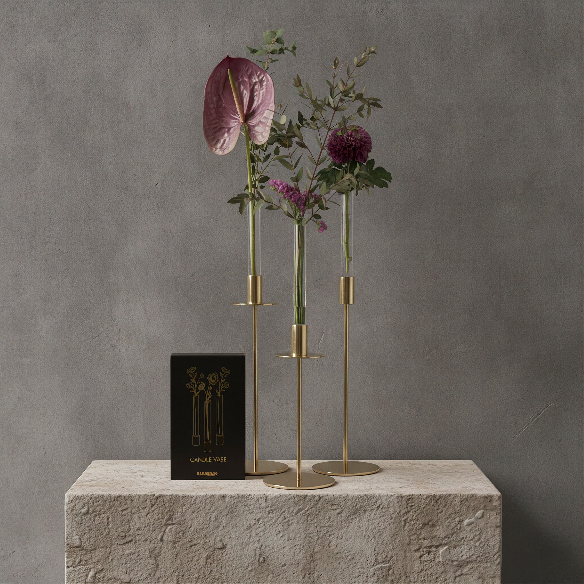 Three Hanataba Candle Vases set in three slim gold-toned candelabra-style holders with round bases, styled with dried and artificial flowers, displayed on a stone pedestal against a textured gray wall. A black box labeled Candelabra No.