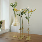 Hanataba candle Vase 3-pack in three gold candle holders with flowers on a wooden surface against a white wall