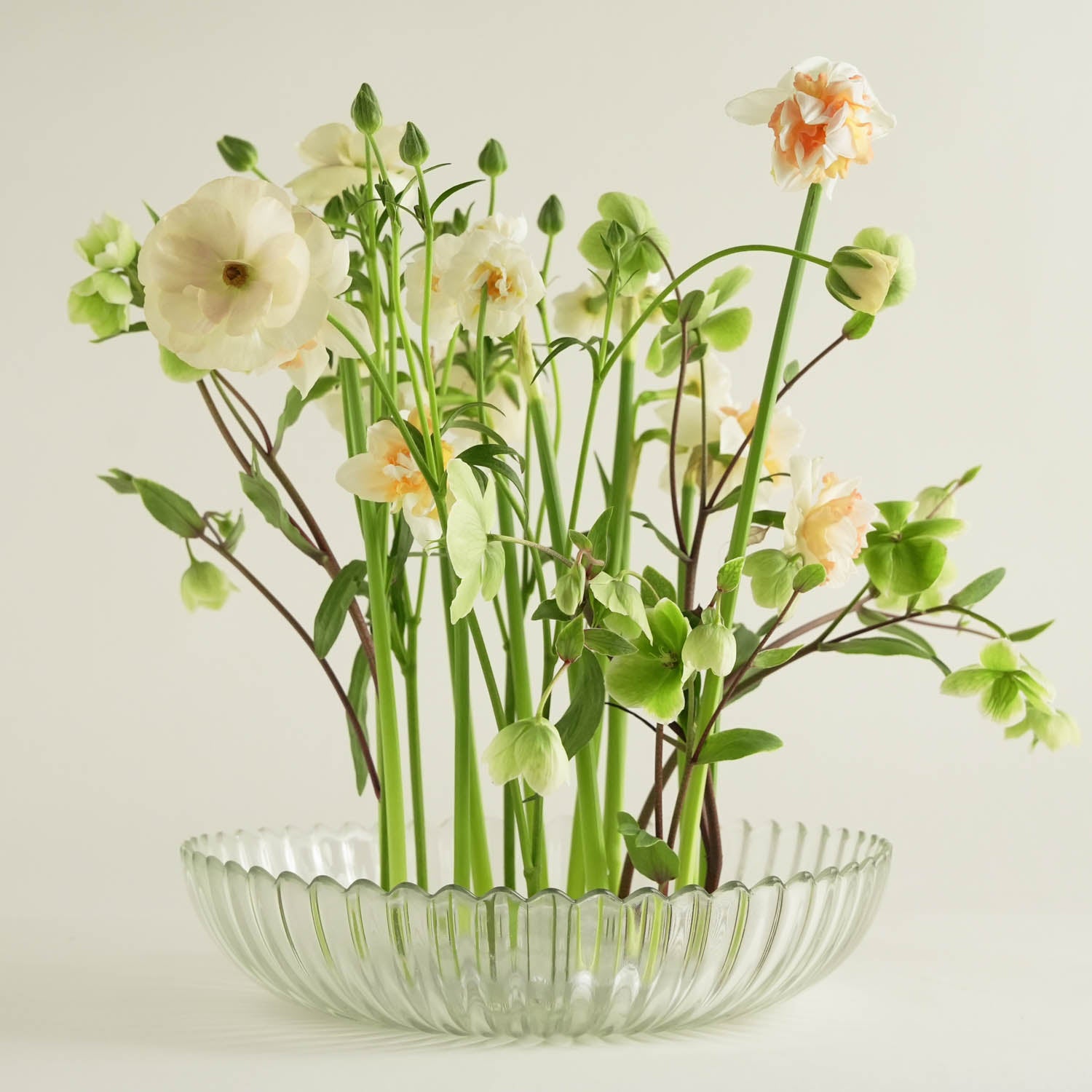 Clear glass bowl with flowers on a kenzan 150 mm acrylic ring on a light background