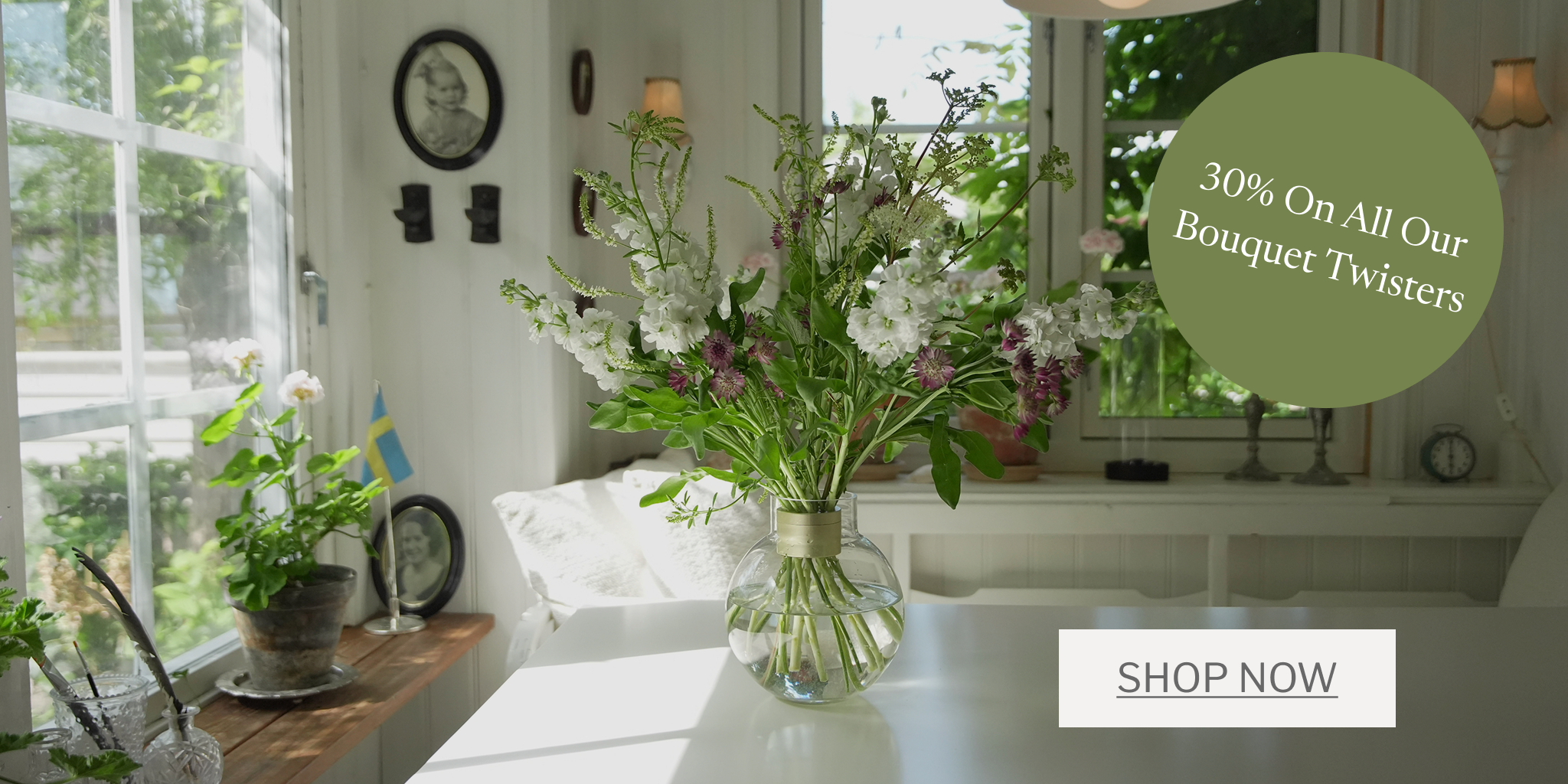 Living room with a vase of flowers, plants, and a 'Shop Now' button for bouquet twisters.