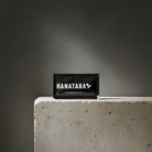HANATABA flower food packaging for enhancing flower longevity standing on a concrete surface with a dark background 
