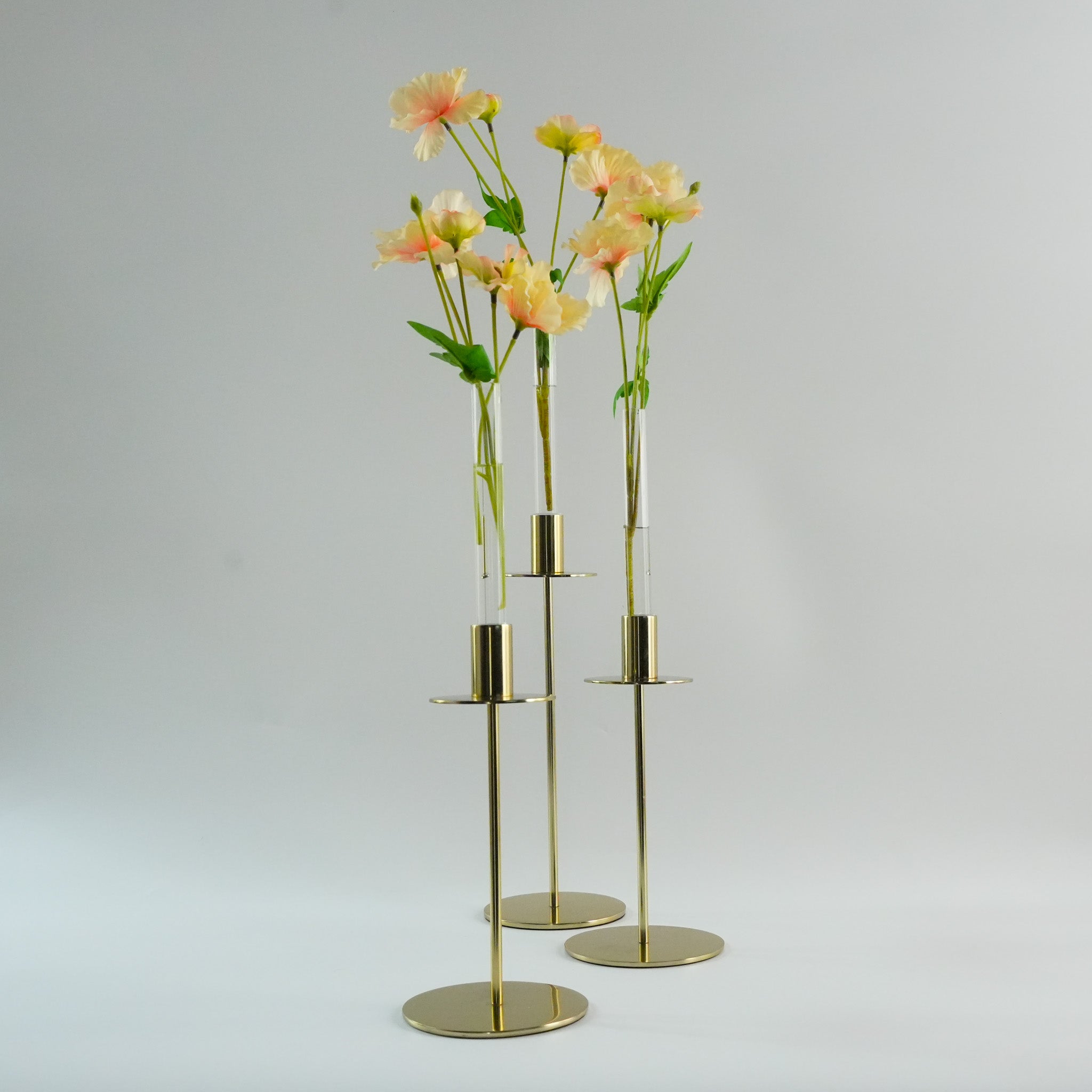 Hanataba Candle Vase 3-Pack in a set of three gold candle holders containing flowers on a gray background