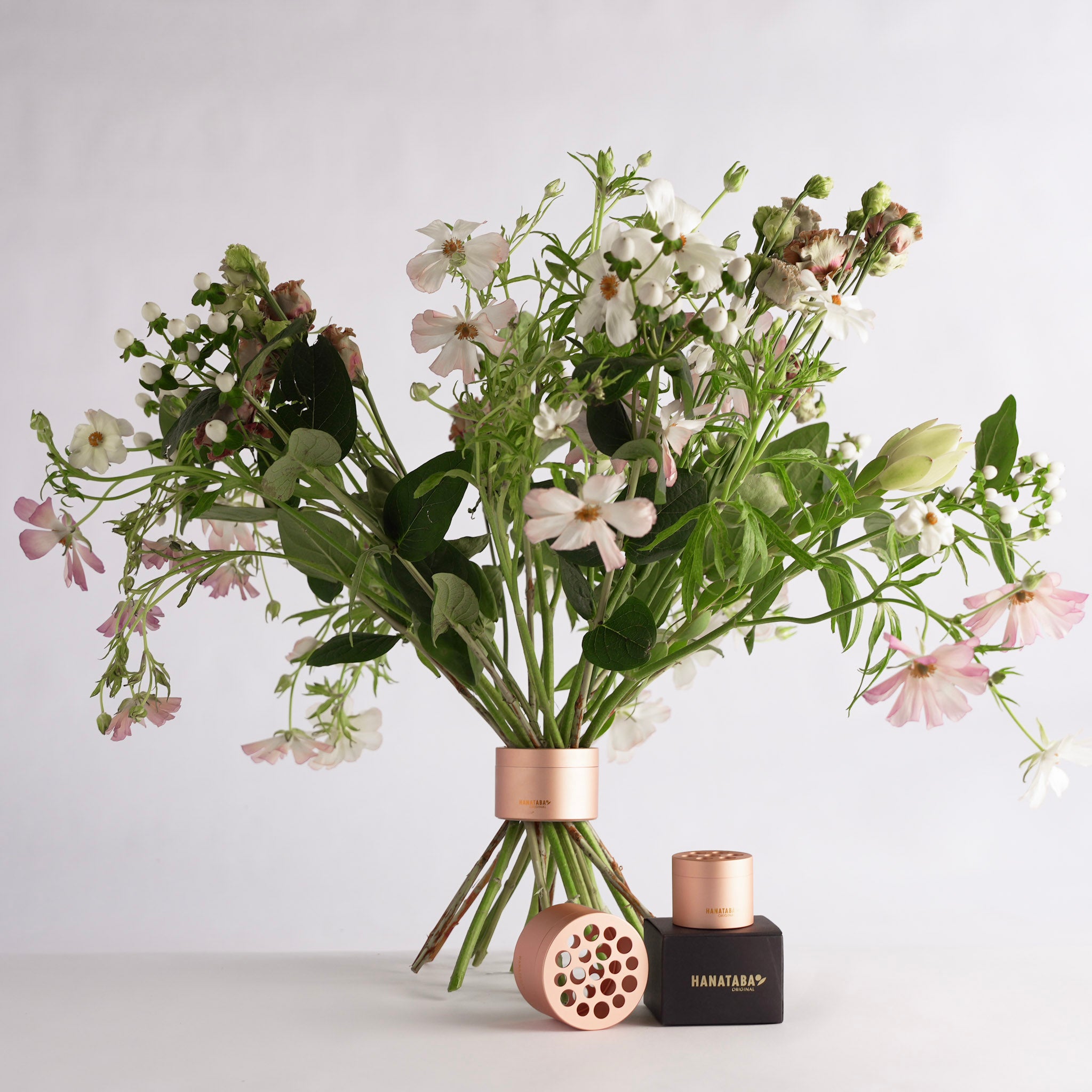Bouquet of flowers inside a hanataba bouquet twister 'Pink Champagne ' on a light gray background
