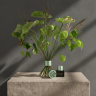 Decorative plant arrangement with a Hanataba bouquet flower twister in color 'Matcha green' on a stone surface against a gray background