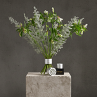 Bouquet of flowers in a Hanataba bouquet flower twister in color 'Pearly Silver' on a concrete block with a dark background
