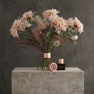 Bouquet of pink flowers in a Hanataba bouquet flower twister in color 'Pink Champagne' with decorative elements on a stone surface against a gray background