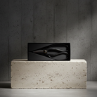 Black rectangular box with a unique japanese scissor design on a concrete block against a gray wall.