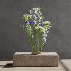 Bouquet of flowers in a 'Hanataba' Kenzan flower frog pin holder ring 120 mm, standing on a concrete block against a gray background