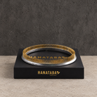 HANATABA ORIGINAL kenzan flower frog ring pin older 20cm/200 mm rests on top of a Black Box with label on a beige colored stone surface in front of a dark grey concrete wall