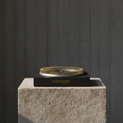 Kenzan 200 mm flower frog ring on a stone block with a dark background