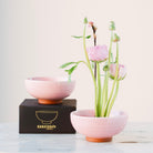 hanataba pink ceramic kenzan 'kobachi' bowl with flowers and a matching bowl on a white surface with a light background