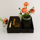 Floral arrangement in a pot with grooming tools and a black box labeled 'HANATABA' on a light gray background.