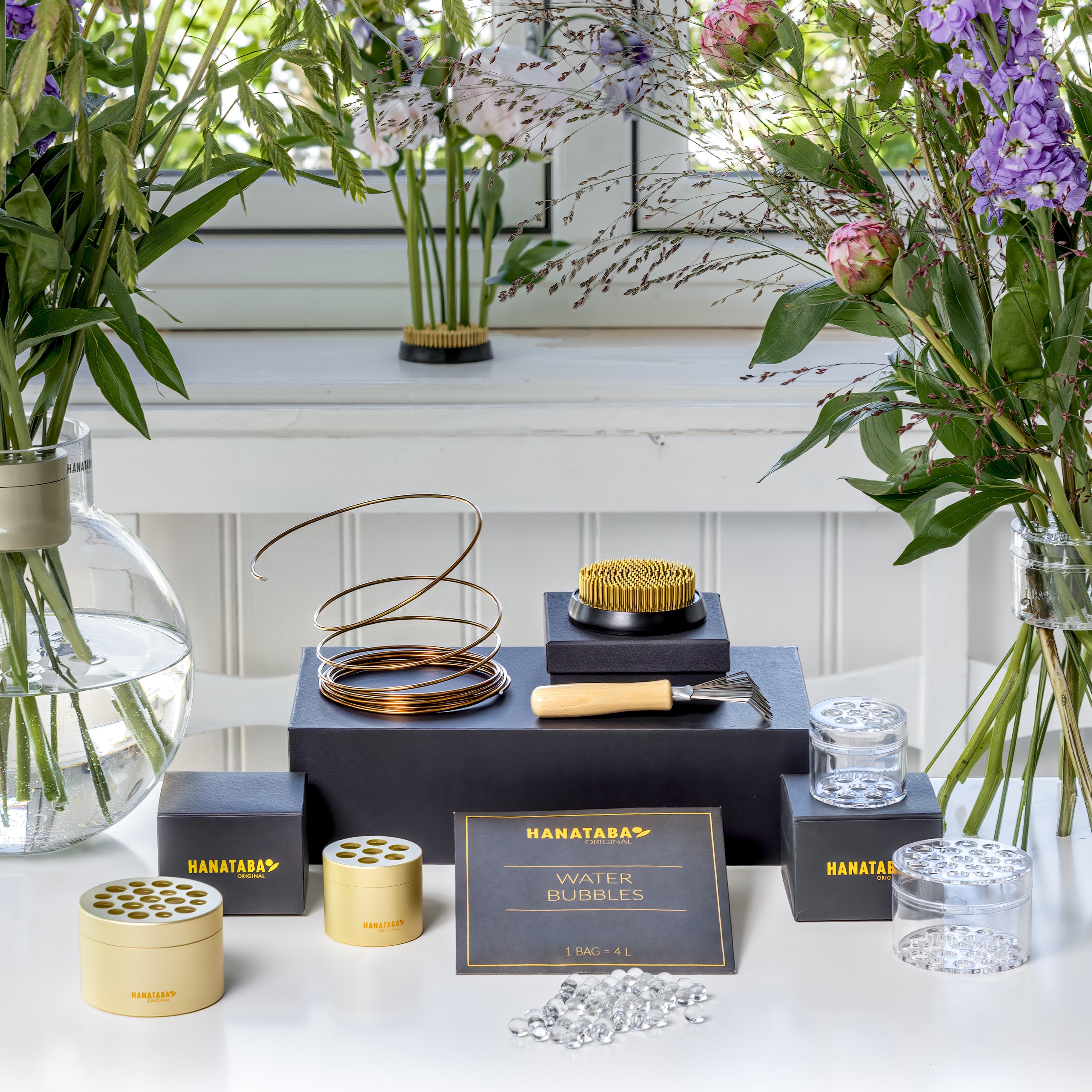 Hanataba Champagne gold and bouquet twister crystal clear, water pearls and a brown bonsai wire kenzan 70 mm alongside with a kenzan brush, used for cleaning your kenzan product display 