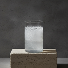 Clear glass with bubbles on a concrete block against a gray background