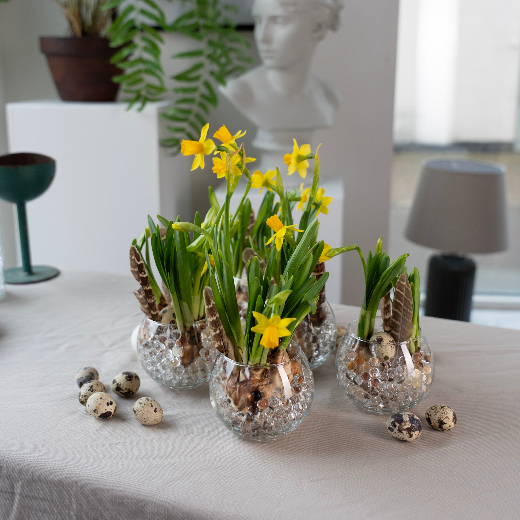 Small glass vases with yellow flowers using hanataba waterbubbles on a table with decorative quail eggs.