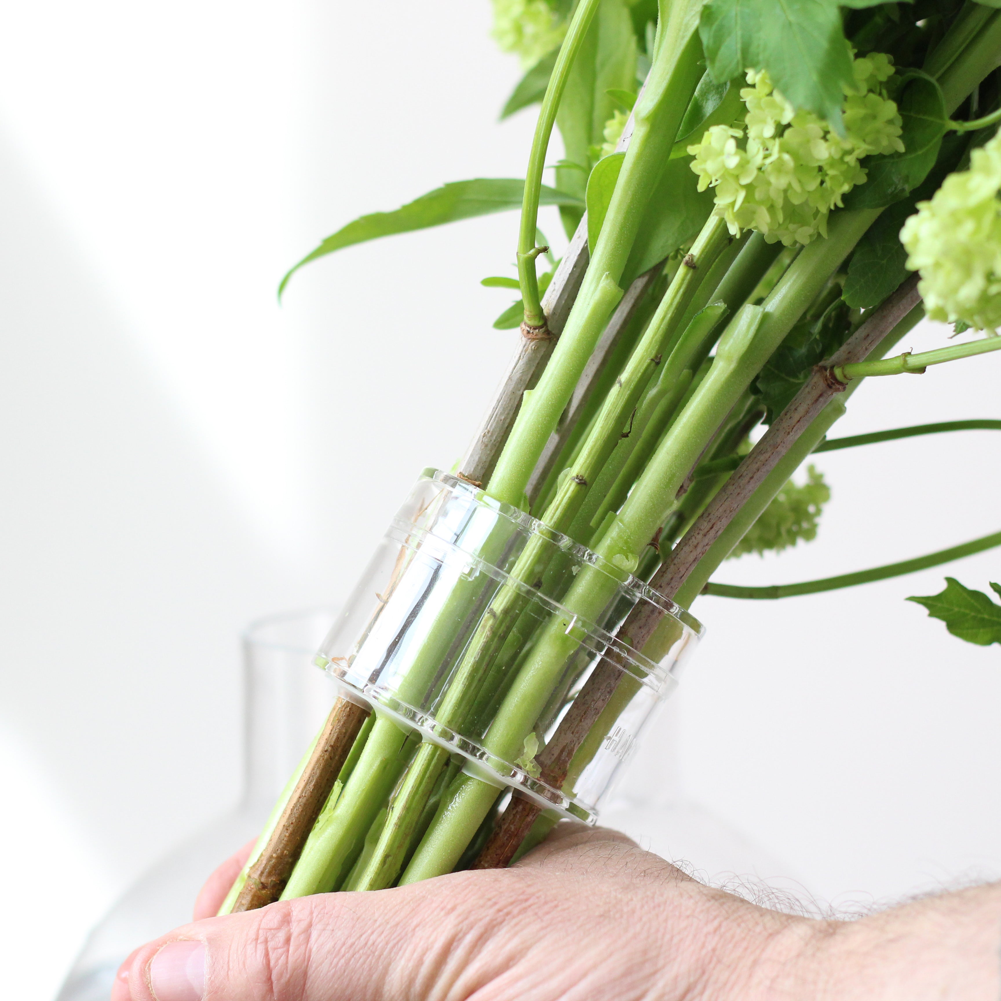 Close-up of a hand securing a bouquet with a Hanataba crystal clear bouquet twister, a transparent tool designed to hold flower stems together elegantly.