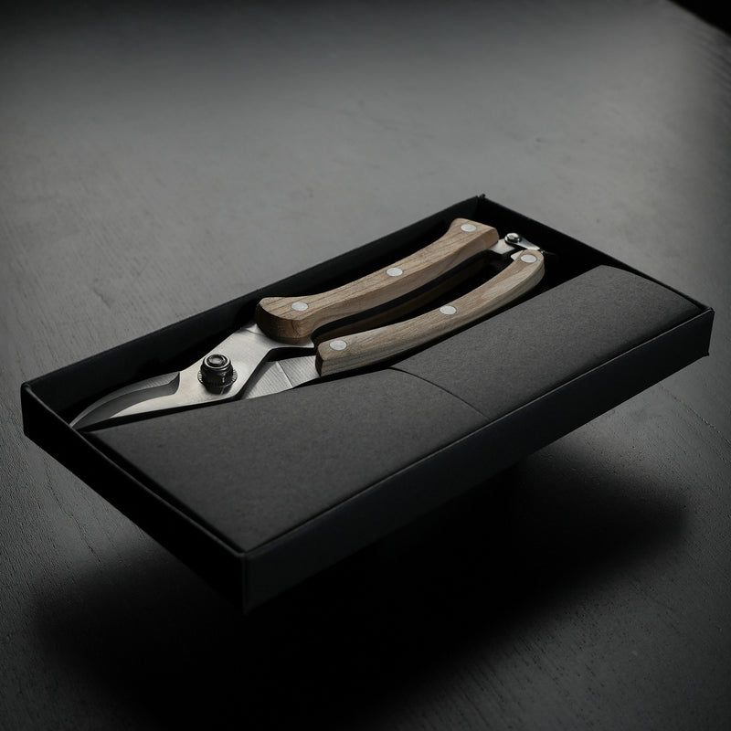 legant, wood-handled secateurs nestled in a sleek black presentation box with subtle branding, designed for precise flower trimming.