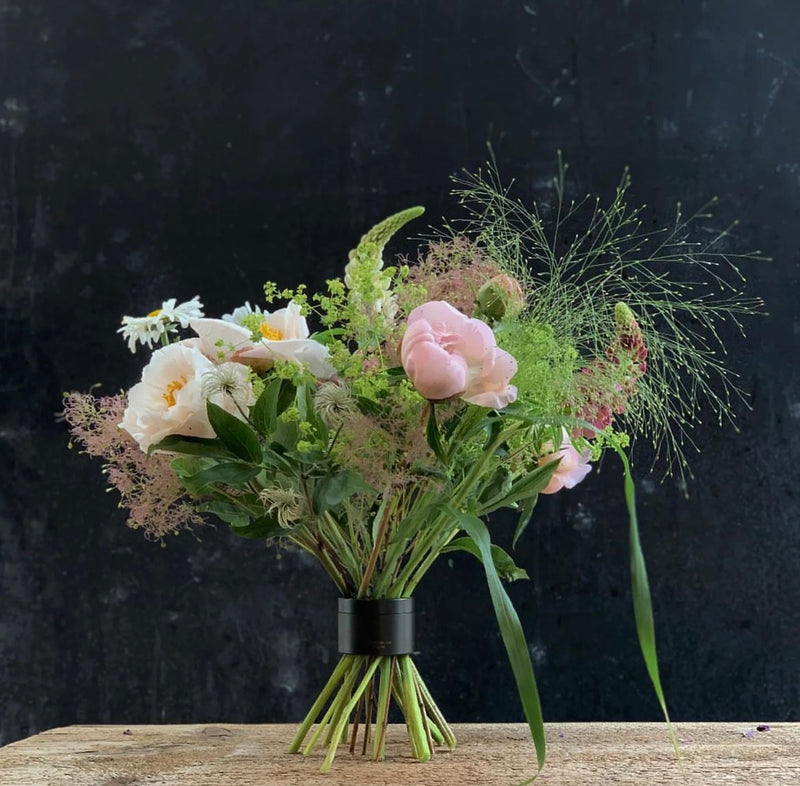A delicate bouquet of pink roses, white flowers, and wispy greenery, neatly secured by a Hanataba Bouquet Twister spiral stem holder.