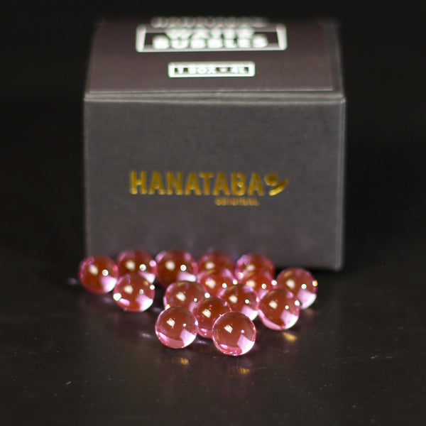 Gleaming pink water bubbles scattered in front of a 'HANATABA ORIGINAL' box, for crafting elegant flower displays.