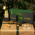 Elegant Ikebana gift set on a festive backdrop with a Christmas tree, featuring a Kenzan rake, flower frog, Hanataba bouquet twister in champagne gold, and a Kenzan ring.