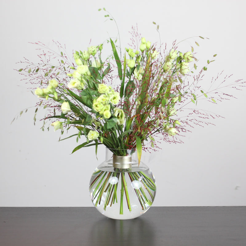 An Ikebana-style floral display featuring fresh green blooms and delicate pink accents, artfully arranged and supported by a Hanataba Spiral Stem holder