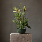 Floral decoration inside a ceramic bowl on a stone block with a gray background