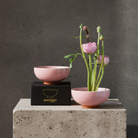 Pink ceramic bowl with flowers on a concrete surface against a gray background