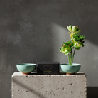 Two turquoise bowls and a black box on a concrete block with a gray background