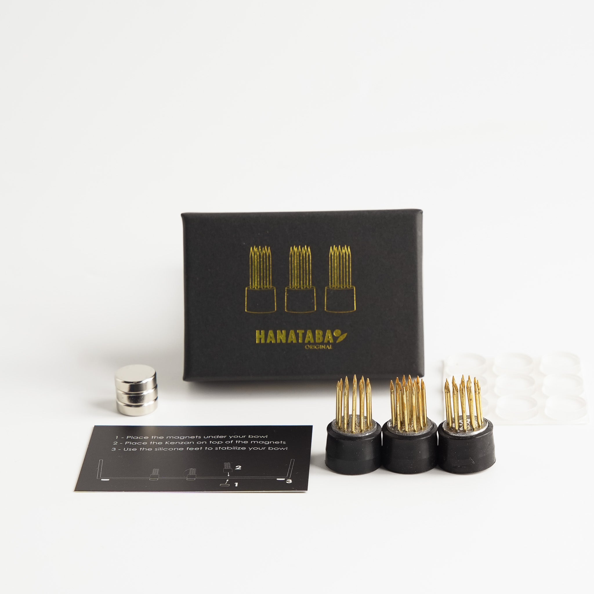 Hanataba magnetic flower frog set including three small kenzans, three magnets, silicone pads, and instruction card, displayed with the black Hanataba gift box.