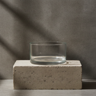 Clear glass vase on a concrete block against a gray background