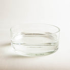 Hanatabaclear glass bowl filled with water in a bright white room.