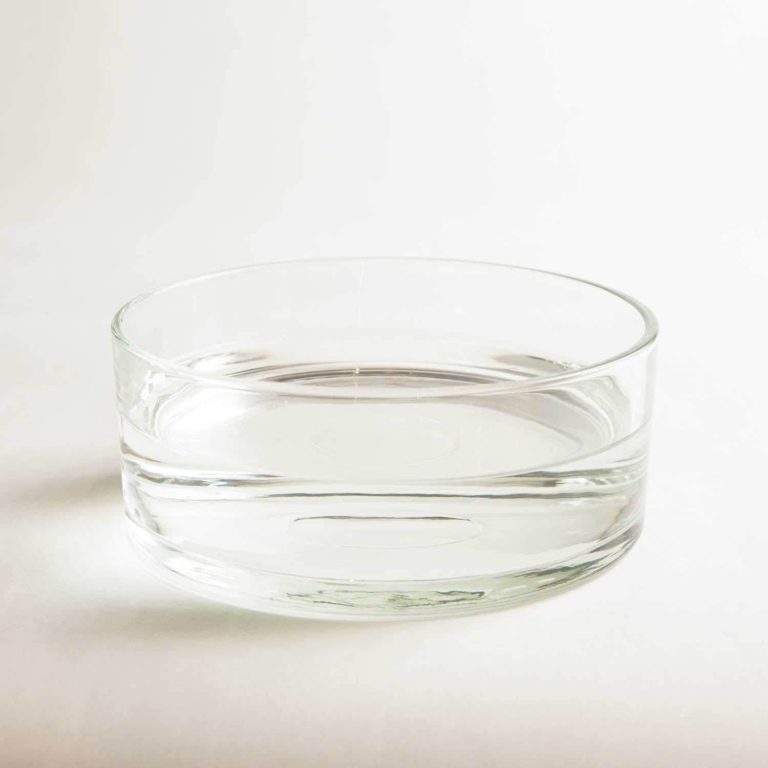 Hanatabaclear glass bowl filled with water in a bright white room.